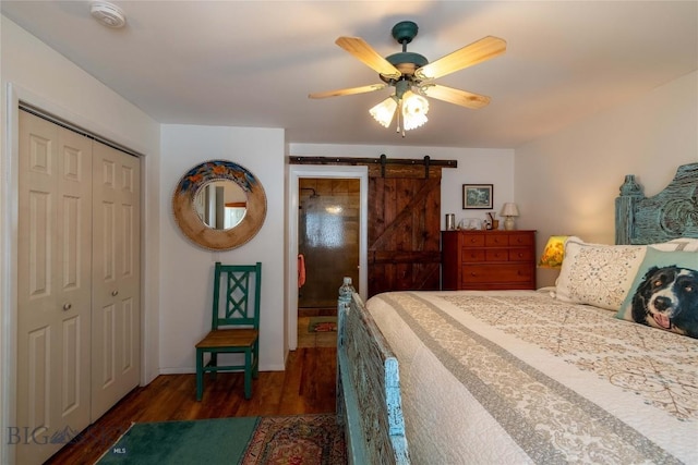 bedroom featuring a closet, a ceiling fan, wood finished floors, and a barn door