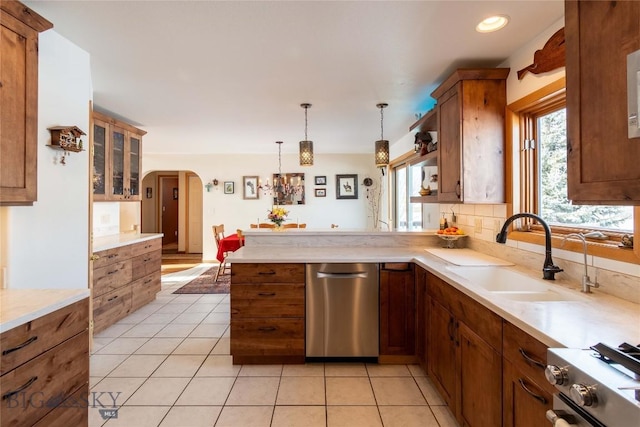 kitchen featuring arched walkways, range, dishwasher, a sink, and light tile patterned flooring