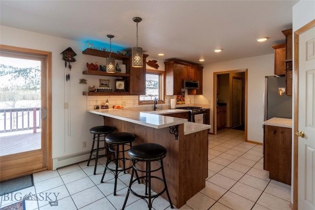 kitchen with stainless steel appliances, a baseboard radiator, backsplash, a peninsula, and a kitchen breakfast bar