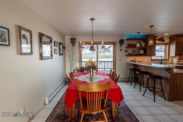 dining room featuring light tile patterned floors, baseboards, a baseboard heating unit, and a notable chandelier