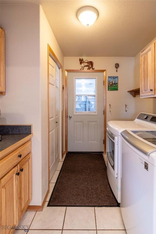 laundry room with light tile patterned flooring, washing machine and dryer, and cabinet space