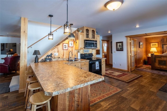 kitchen with a breakfast bar, stainless steel microwave, glass insert cabinets, a sink, and black / electric stove