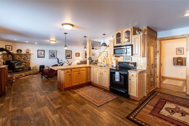 kitchen featuring black electric range oven, stainless steel microwave, open floor plan, a wood stove, and a peninsula