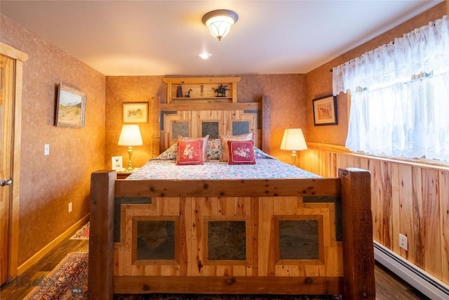 bedroom featuring baseboards, a baseboard heating unit, and dark wood finished floors