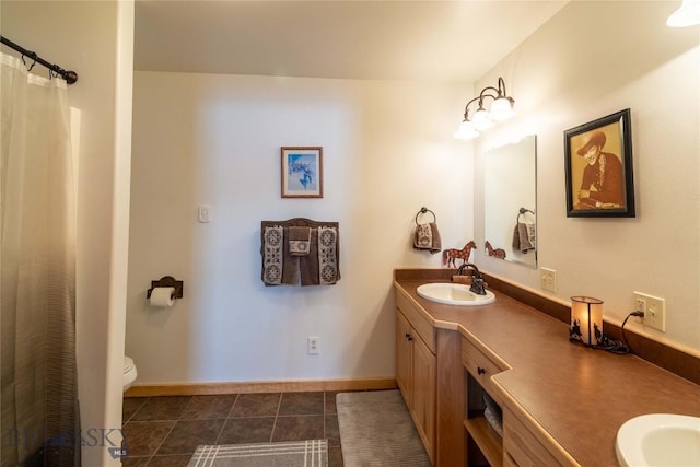 full bath with double vanity, toilet, a sink, baseboards, and tile patterned floors