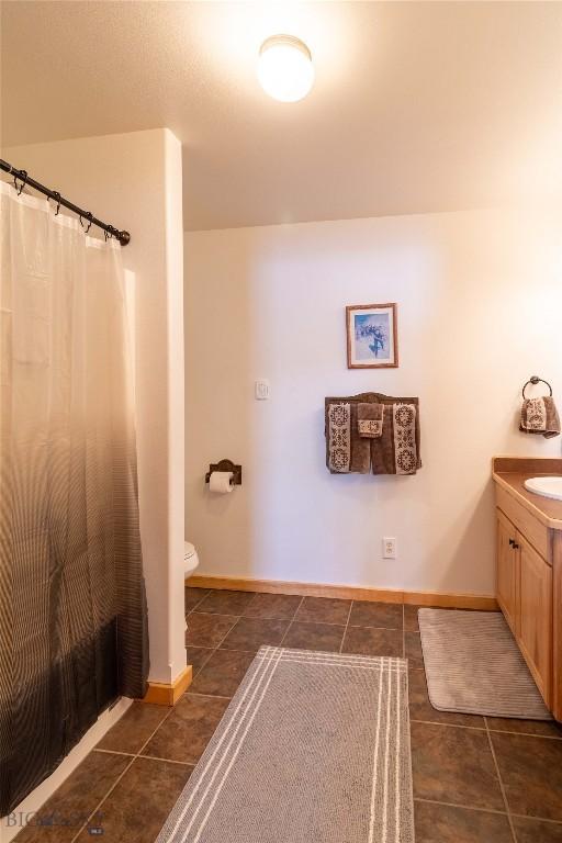 full bathroom featuring a shower with shower curtain, toilet, vanity, baseboards, and tile patterned floors