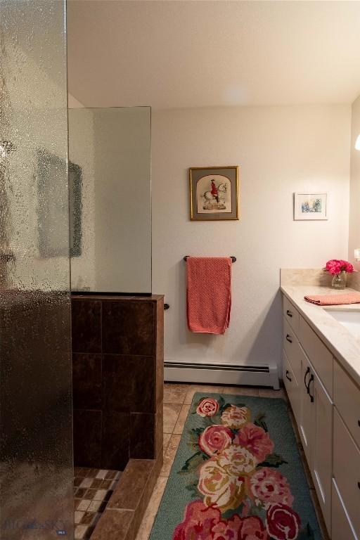 bathroom with tile patterned floors, walk in shower, baseboard heating, and vanity