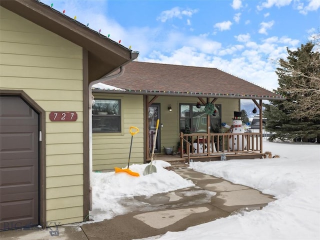 view of front of property featuring a shingled roof, covered porch, and an attached garage