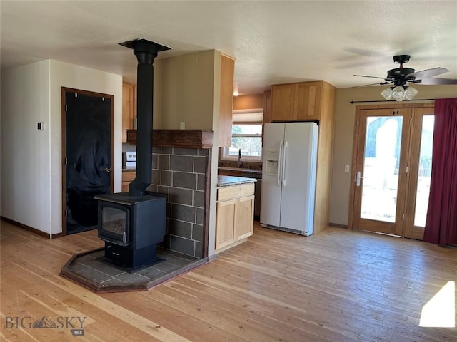 727 Mirza Way, Ennis, MT 59729 - kitchen featuring white refrigerator with ice dispenser, a wood stove, light wood-style flooring, and a ceiling fan