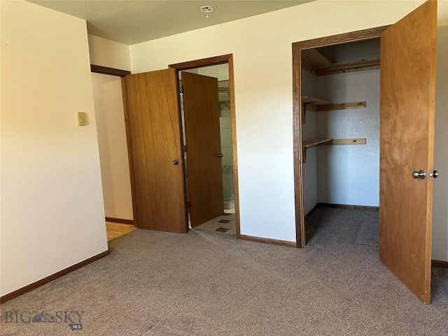 unfurnished bedroom with a spacious closet, carpet floors, and baseboards