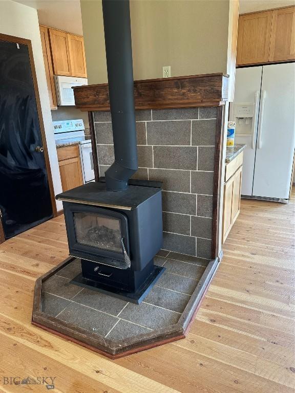 727 Mirza Way, Ennis, MT 59729 - detailed view of white appliances, light wood-style floors, and a wood stove