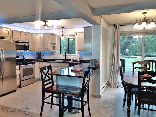 kitchen with dark countertops, a baseboard radiator, stainless steel appliances, a chandelier, and a sink