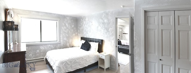 bedroom featuring a closet, baseboard heating, and wood finished floors