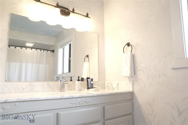 full bath featuring a textured wall and vanity