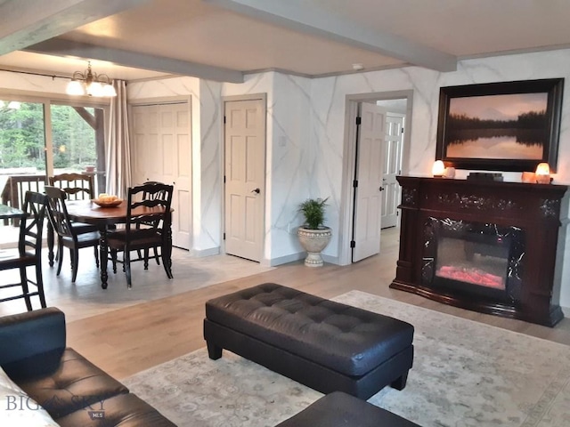 living room featuring a chandelier, a high end fireplace, beam ceiling, and light wood finished floors