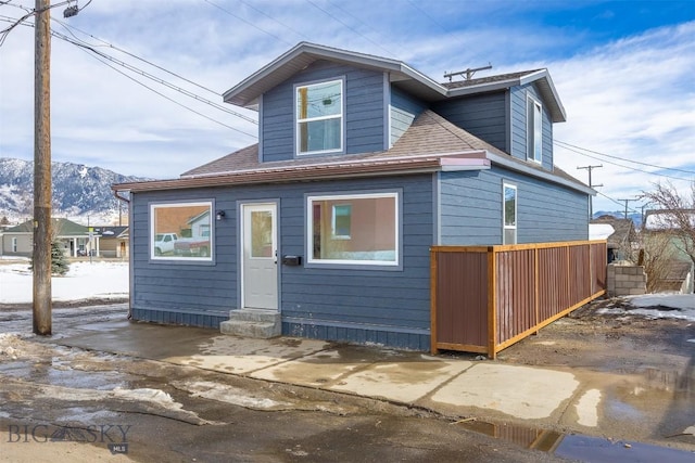 back of property with a shingled roof and a mountain view