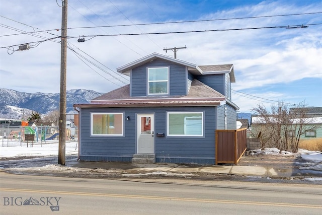 bungalow with entry steps, fence, a mountain view, and roof with shingles