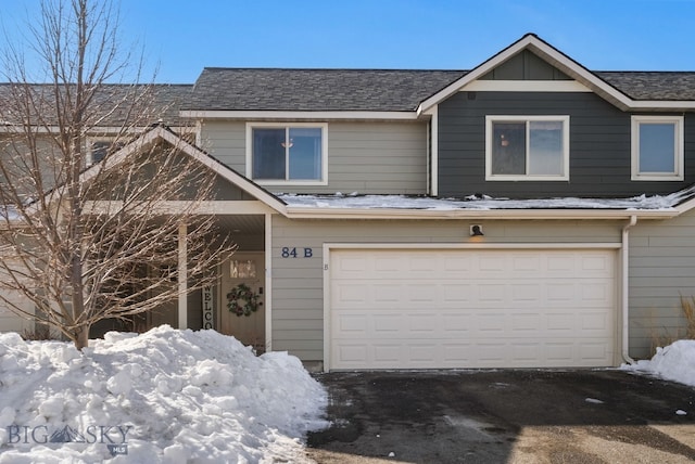 view of property with an attached garage, a shingled roof, and aphalt driveway