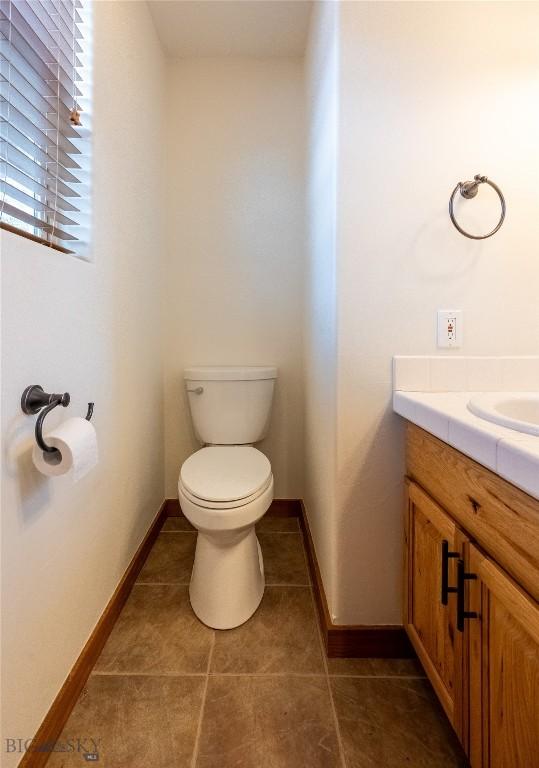 2212 Sourdough Rd, Bozeman, MT 59715 - half bathroom with toilet, vanity, tile patterned flooring, and baseboards