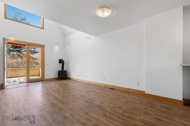 1281 Stoneridge Unit A, Bozeman, MT 59718 - unfurnished living room featuring wood finished floors, a high ceiling, and a wood stove