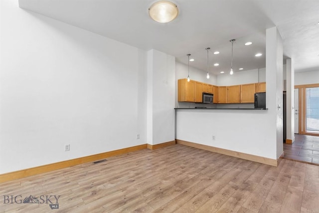 1281 Stoneridge Unit A, Bozeman, MT 59718 - kitchen with stainless steel microwave, recessed lighting, light wood finished floors, hanging light fixtures, and dark countertops