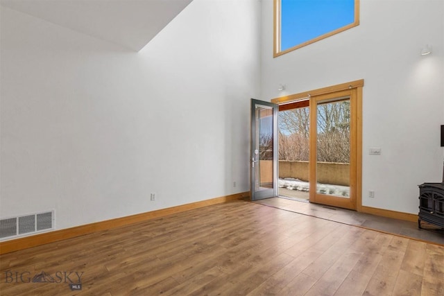 1281 Stoneridge Unit A, Bozeman, MT 59718 - unfurnished living room featuring a wood stove, healthy amount of natural light, a towering ceiling, and wood finished floors