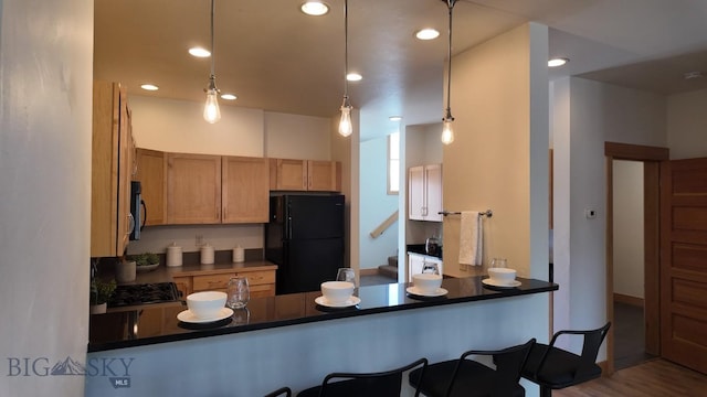 1281 Stoneridge Unit A, Bozeman, MT 59718 - kitchen with freestanding refrigerator, a peninsula, dark countertops, wood finished floors, and recessed lighting