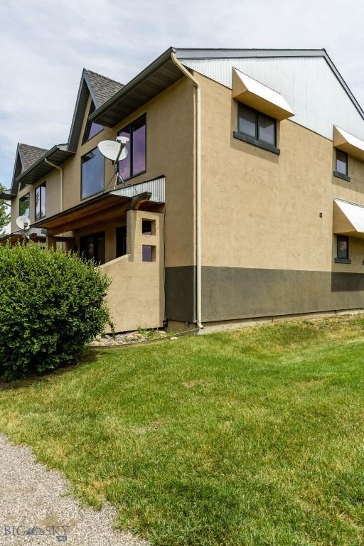 1281 Stoneridge Unit A, Bozeman, MT 59718 - view of side of property with stucco siding and a lawn
