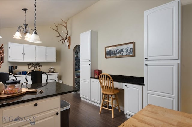 kitchen featuring lofted ceiling, white cabinetry, dark wood-style floors, built in desk, and pendant lighting