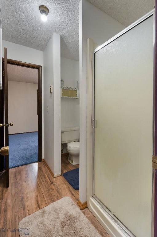 bathroom featuring a textured ceiling, wood finished floors, and a shower stall