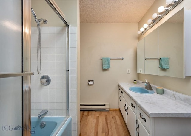 full bath featuring a baseboard heating unit, washtub / shower combination, a textured ceiling, vanity, and wood finished floors