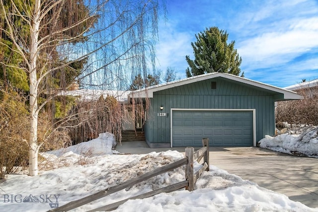 snow covered garage with driveway