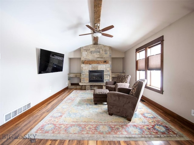 living area featuring baseboards, visible vents, lofted ceiling with beams, wood finished floors, and a fireplace