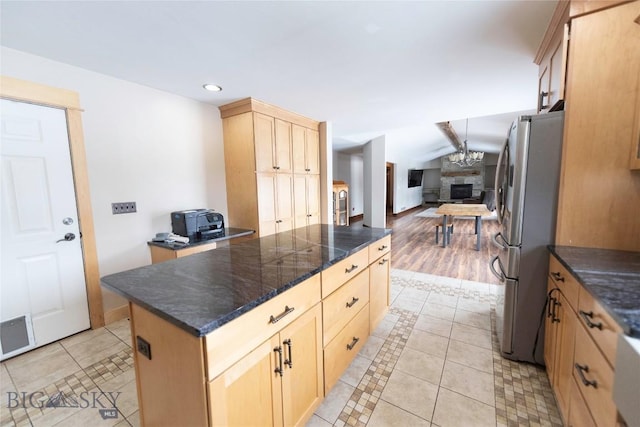 kitchen with light tile patterned floors, lofted ceiling, open floor plan, freestanding refrigerator, and light brown cabinets