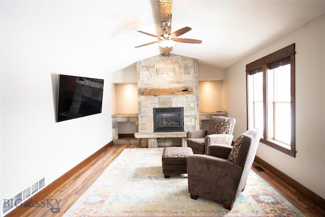 living area with lofted ceiling, visible vents, a fireplace, and wood finished floors