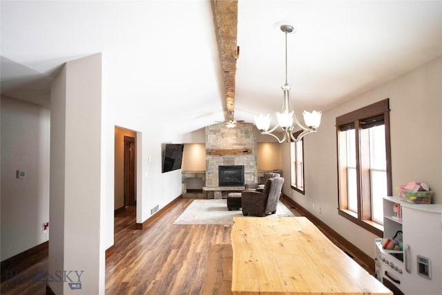 living area featuring dark wood-style floors, vaulted ceiling with beams, a fireplace, a chandelier, and baseboards