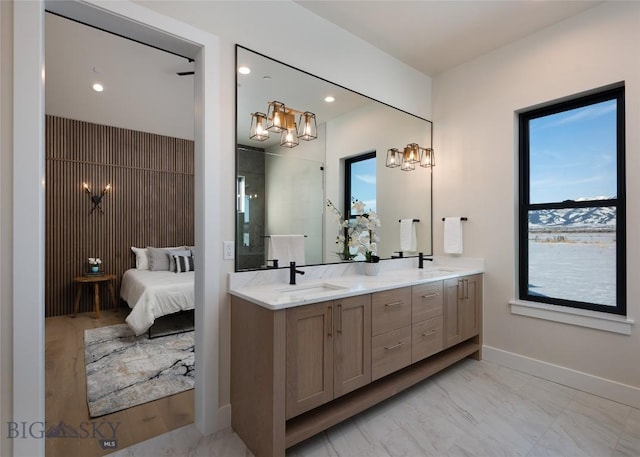 full bathroom featuring marble finish floor, a sink, baseboards, and double vanity