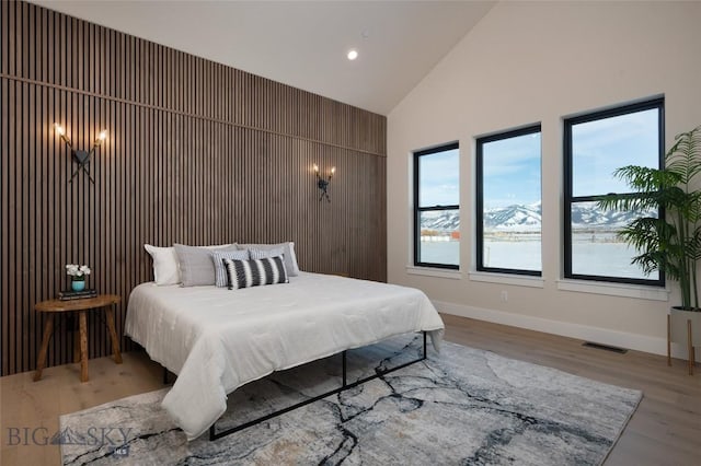 bedroom with baseboards, visible vents, wood finished floors, high vaulted ceiling, and recessed lighting