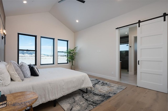 bedroom featuring light wood finished floors, a barn door, baseboards, lofted ceiling, and recessed lighting