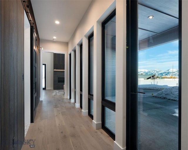 hallway with light wood-style floors, recessed lighting, a mountain view, and a barn door