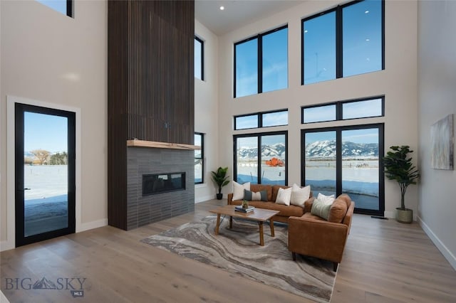 living room featuring light wood-style floors, baseboards, and a tile fireplace