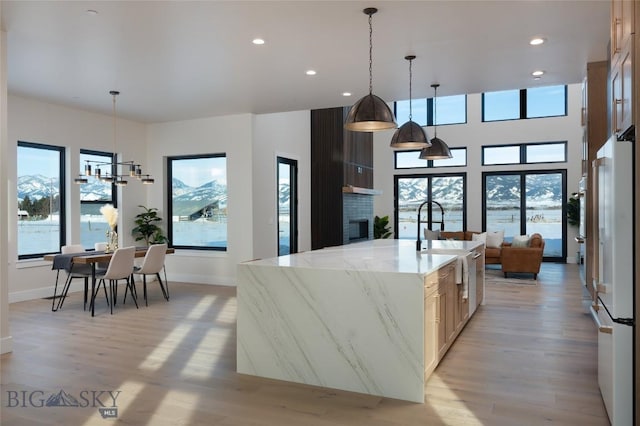 kitchen with a spacious island, light wood-type flooring, freestanding refrigerator, and a healthy amount of sunlight