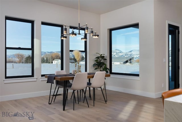 dining room with a mountain view, a notable chandelier, baseboards, and wood finished floors