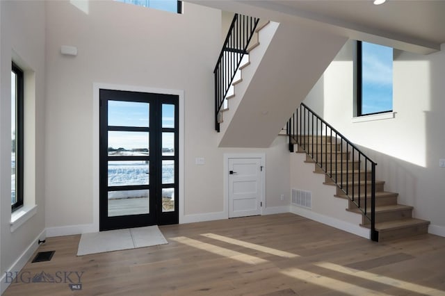 entryway with a high ceiling, visible vents, and wood finished floors