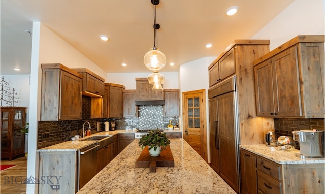 kitchen featuring light stone counters, recessed lighting, a sink, hanging light fixtures, and appliances with stainless steel finishes