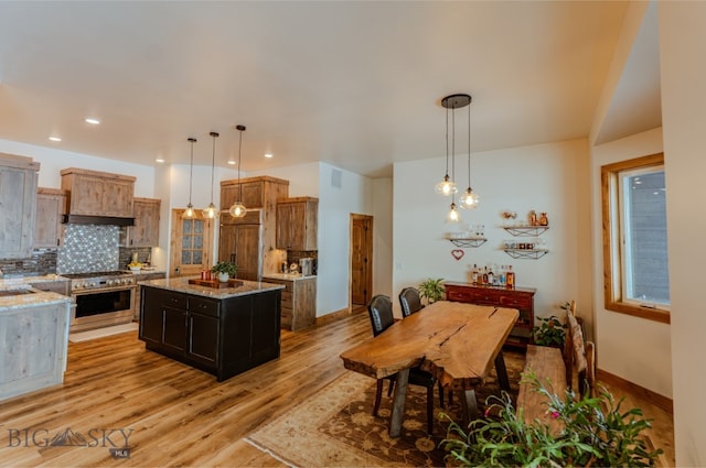 kitchen featuring wall oven, decorative backsplash, light wood-style flooring, a kitchen island, and light stone countertops