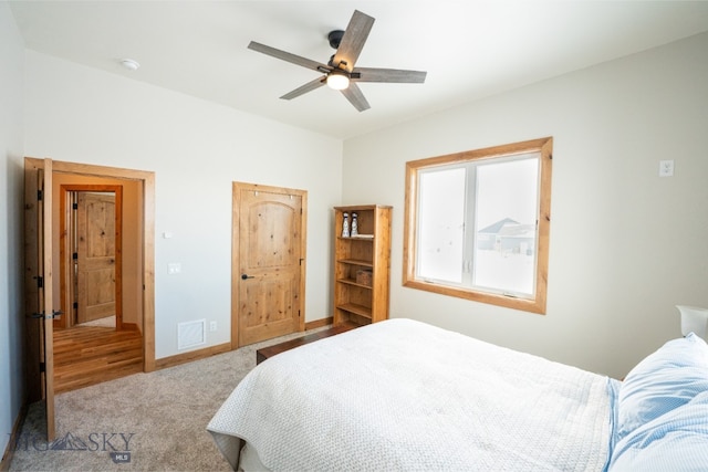 carpeted bedroom with baseboards, visible vents, and a ceiling fan