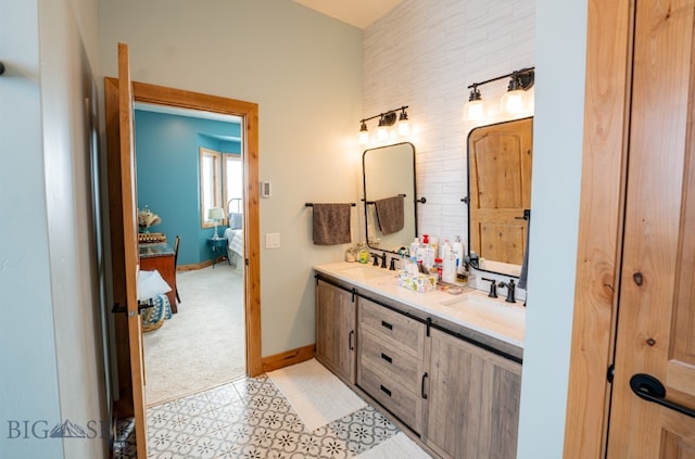 ensuite bathroom featuring double vanity, baseboards, a sink, and ensuite bathroom