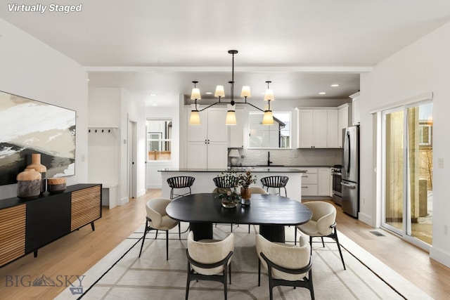 dining space featuring recessed lighting, a notable chandelier, and light wood finished floors