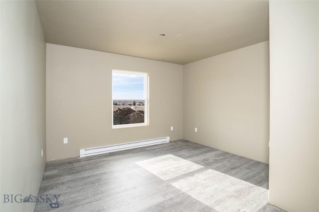 unfurnished room featuring a baseboard heating unit and wood finished floors